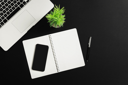 Office table desk with, laptop smart phone and notebook on black background. Top view.の写真素材