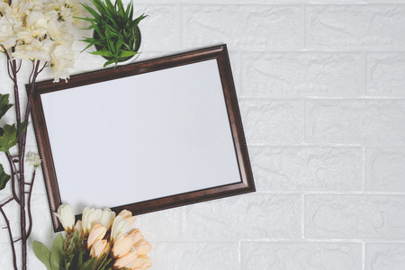 Wood frame with potted plant and flowers on white brick background. Rustic nostalgia with copy space.の写真素材