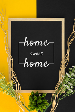 Home sweet home on black and yellow background with rustic wood sticks and flower.の写真素材