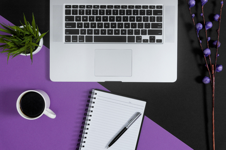 Laptop and notebooks on purple and black background. Work planning concept.の写真素材