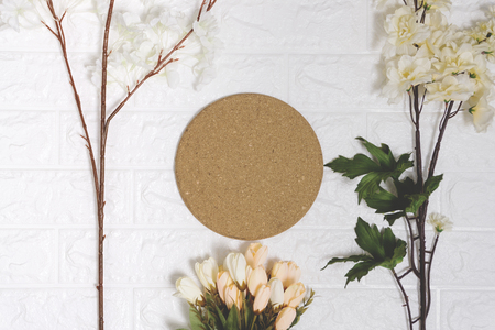 Round cork board and flowers on white brick background. Copy space.の写真素材