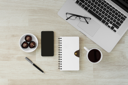 Laptop and notebooks with hot coffee and cookies on wood background. Morning rustic home office.の写真素材