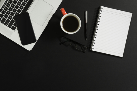 Laptop, smart phone, notebook, eyeglasses and coffee on black background.の写真素材