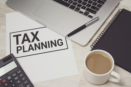 Tax Planning written on white paper with laptop computer and coffee cup. Business and finance concept.の写真素材