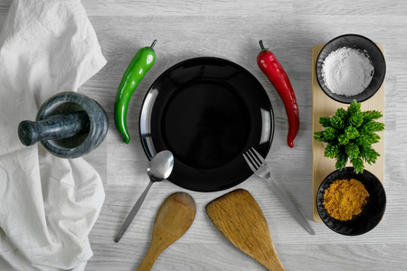 Cutlery set with spices, chilies and mortar on wood table background. Kitchen utensils.の写真素材