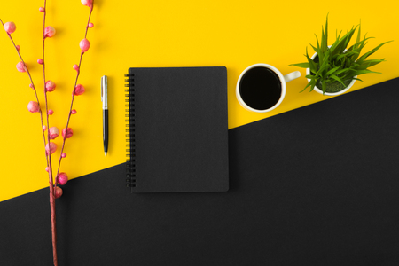 Black sketch pad with coffee cup on yellow and black background.の写真素材