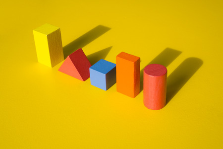 Wooden building blocks toy with shadow isolated on yellow background.の写真素材