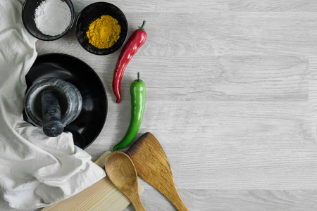 Cutlery set with spices, chilies and mortar on wood table background. Kitchen utensils.の写真素材
