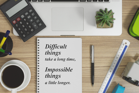 Office supplies on wood office desk. Notebook with motivational and inspirational quote.の写真素材
