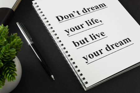 Notebook with wisdom quote on black working desk.の写真素材