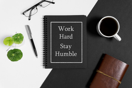 Notebook with wisdom quote and coffee cup on black and white background.の写真素材