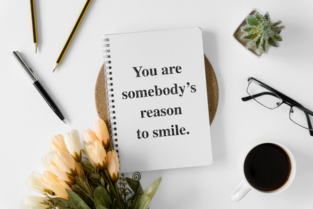 Notebook with wisdom quote and coffee cup on white background.の写真素材