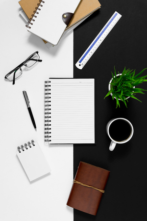 Notebook with coffee cup and personal items on black and white background.の写真素材