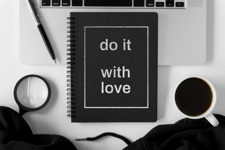 Notebook with wisdom quote and laptop on white office table.の写真素材