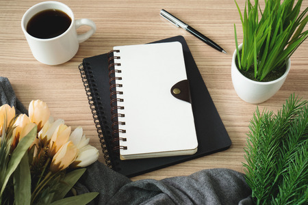 Spiral notebooks with coffee cup and flower on wood desk.の写真素材