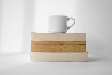 Coffee cup on top of stack of books with white background.の写真素材