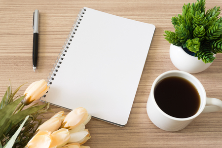 Notebook with coffee cup, potted plant and flower on wood desk. Text copy space.の写真素材