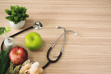 Stethoscope with apple fruits on wood background. Healthy lifestyles concept.の写真素材