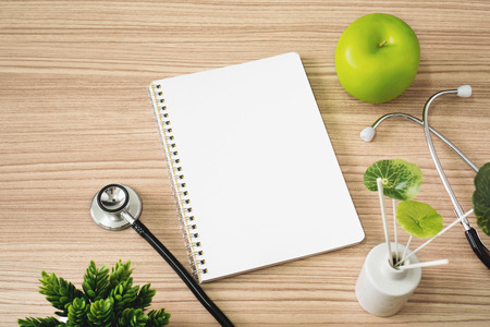 Stethoscope with notebook and apple fruits on wood background. Text copy space.の写真素材