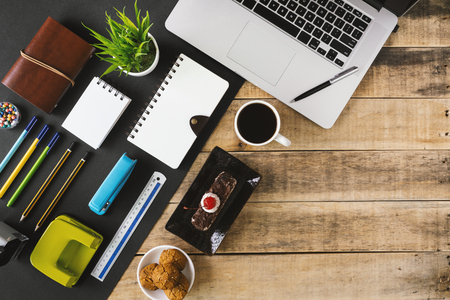 Office supply items, butterscotch cake and coffee on rustic wood. Flat lay.の写真素材