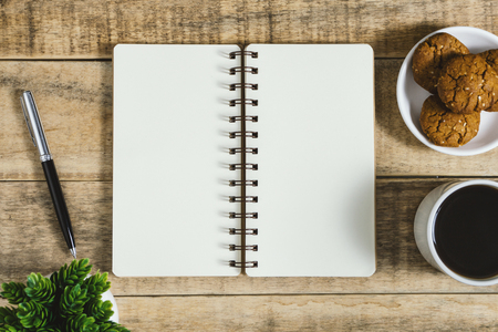 Notebook, cookies and cup of coffee on rustic wood. Flat lay with text copy space.の写真素材