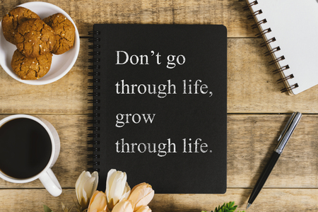Black notebook with wisdom quote, cookies and cup of coffee on rustic wood. Flat lay with text copy space.の写真素材