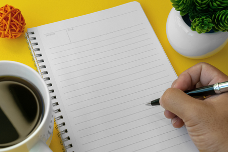 Hand holding a pen and writing on notebook. Text copy space.の写真素材