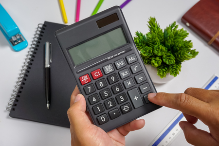 Hands holding a calculator on top of office working table.の写真素材