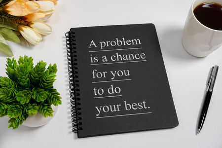 Notebook with wisdom quote and coffee cup on white background.の写真素材