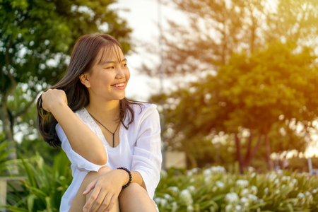 Happy smiling young Asian teenage girl sitting and flipping her hair.の写真素材
