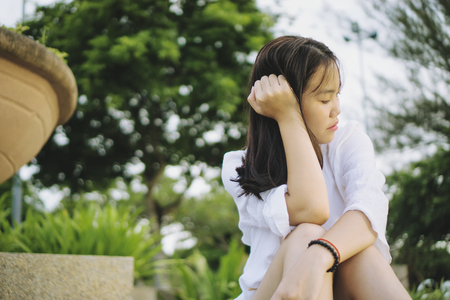 Sad young Asian woman sitting in a park.の写真素材