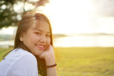 Young Asian girl in a public park near the beach during sunset. Portrait shot from side view.の写真素材