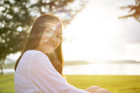Young Asian girl in a public park near the beach during sunset. Portrait shot from side view.の写真素材