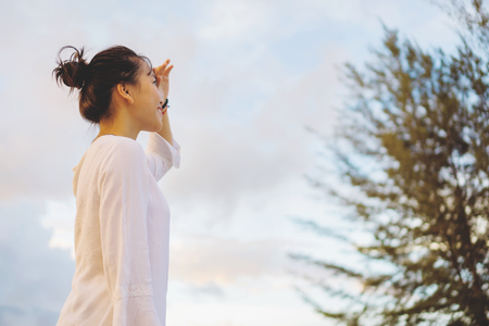 Young woman looking far away in a park during sunset.の写真素材