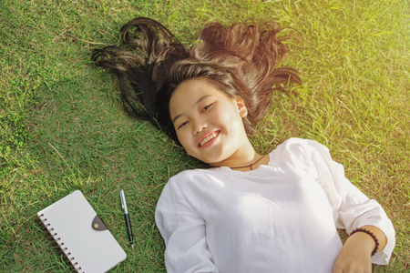 Happy young lady lying and resting on green grass during set. Top view lying down face upwardsの写真素材
