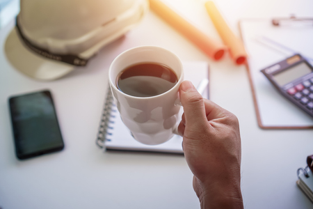 Hand holding coffee mug while taking a break from work. Project management concept.の写真素材