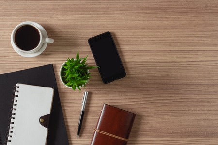 Notepad, coffee and mobile phone on wood background. Home business office supply.の写真素材