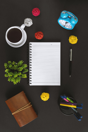 Notepad, coffee and alarm clock on black background. Office table still life.の写真素材
