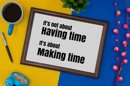 Wood frame, clock and coffee mug on blue and yellow background. Inspirational quote.