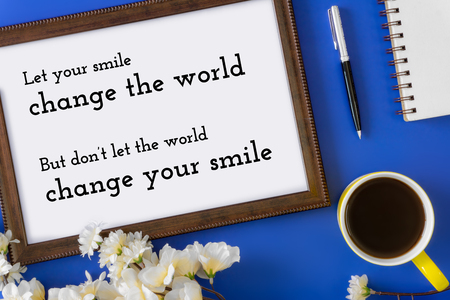 Wood frame, notebook and coffee mug on blue background. Inspirational quote about positive lifestyles.の写真素材
