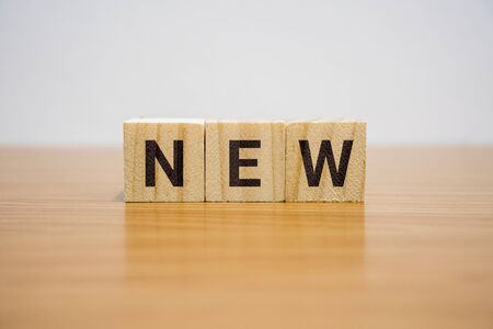 Wooden block on desk with the word New.