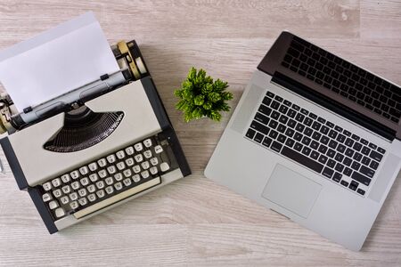 Overhead view of old typewriter with paper sheet and laptop side by side.の写真素材