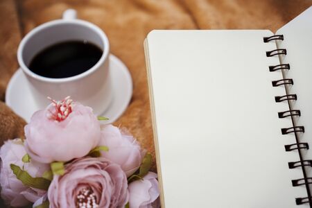 Selective focus view of notebook, flower and coffee cup on blanket.の写真素材