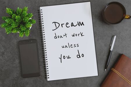 Overhead view of notebook, mobile phone, pen and coffee cup on dark gray background. Inspirational life quote on notepad.の写真素材