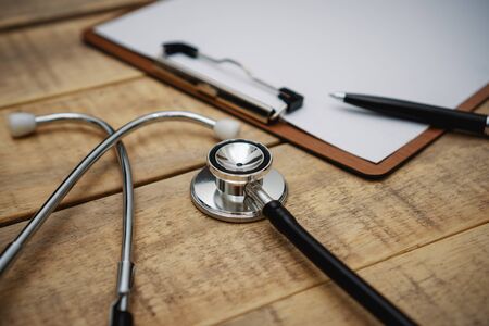 Close up view of stethoscope and clipboard on wood background.の写真素材