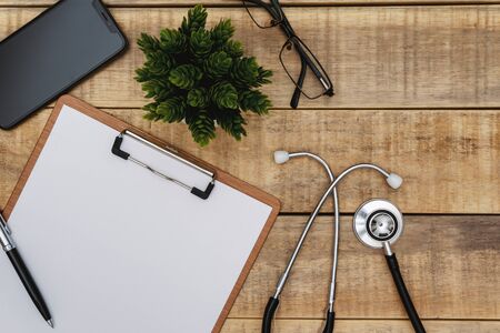 Overhead view of stethoscope and clipboard on wood background.の写真素材