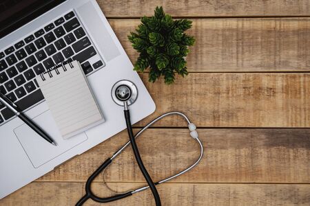 Overhead view of laptop and stethoscope on wood background.の写真素材