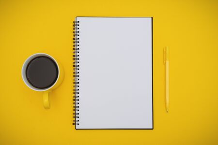 Overhead View of Notepad, Pen and Coffee Cup on Yellow Backgroundの写真素材