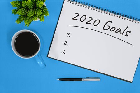 2020 Goals. Overhead View of Notepad and Coffee Cup on Blue Backgroundの写真素材