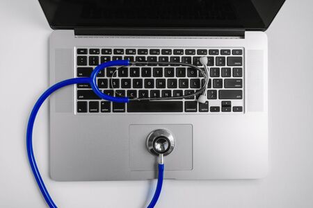 Overhead View of Stethoscope on Laptop Over White Deskの写真素材